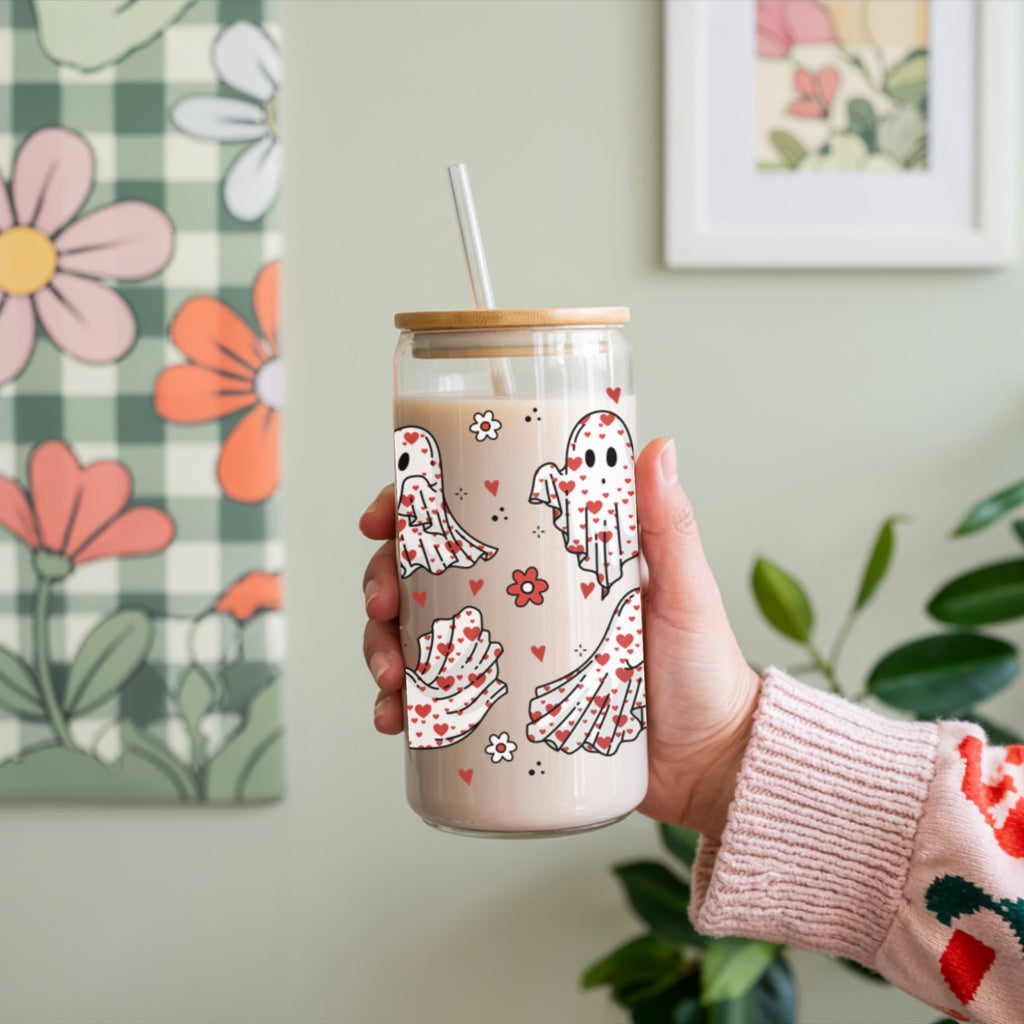 Hand holding a tumbler with cartoon ghost designs against a floral and checkered background