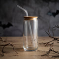 20oz clear glass jar with straw and wooden lid on a dark background with bats and branches