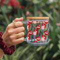 Clear mug with red and pink lip designs held by a hand against a blurred green background
