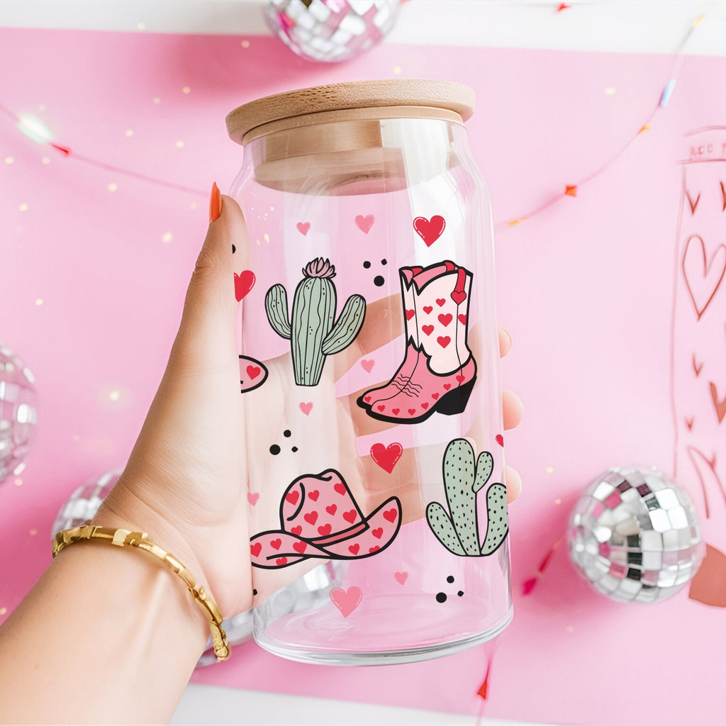 Glass jar with cowboy boot and cactus design held by a hand on a pink background