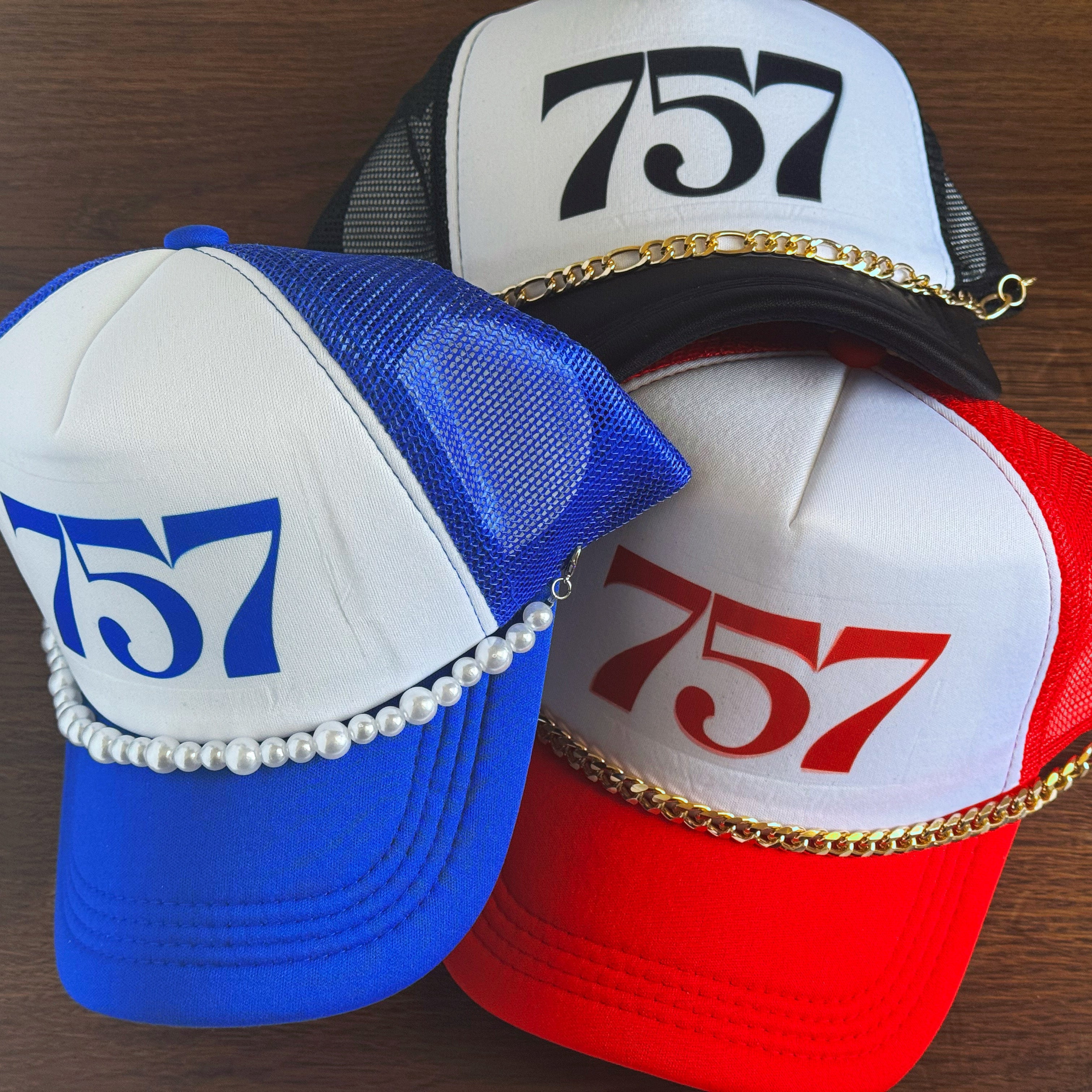 Three trucker caps with '757' area code on a wooden surface