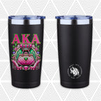 Two views of a black insulated tumbler with a clear lid on a light gray patterned background. The left tumbler shows a colorful graphic of a pink quilted handbag under the letters 'AKA' in pink and green, while the right tumbler shows a silver CoRo logo reading 'Gifts Stationery Beauty'.