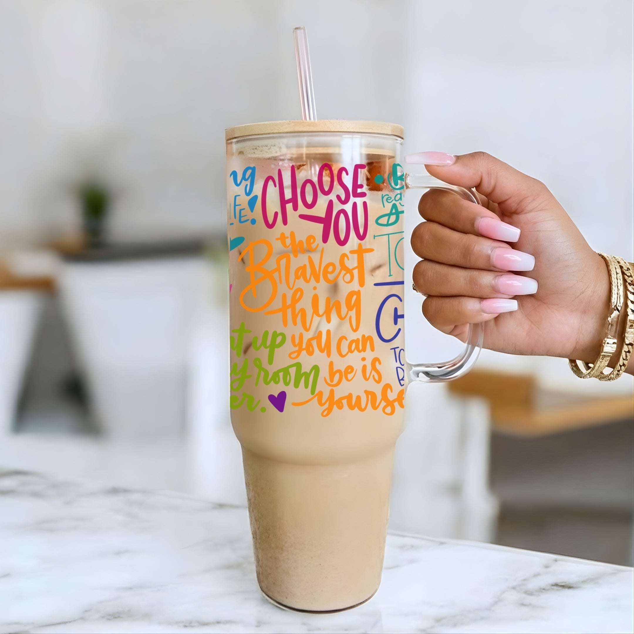 Nik Austin's hand holding a tumbler with motivational quote on a marble surface