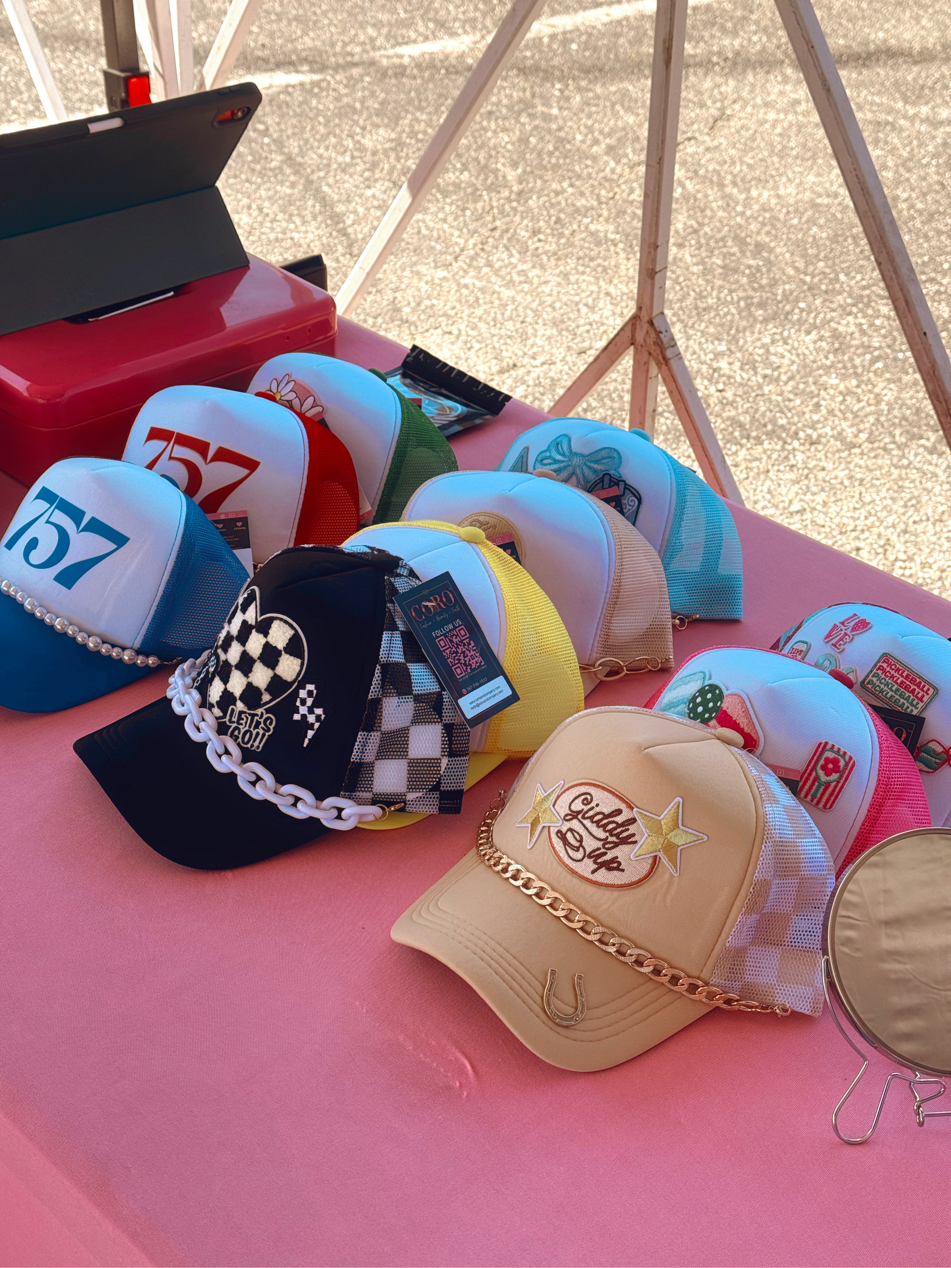Collection of various trucker hats on a pink surface with a blurred background
