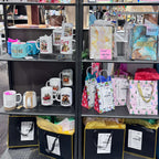 Display case with various merchandise including mugs, keychains, and postcards.