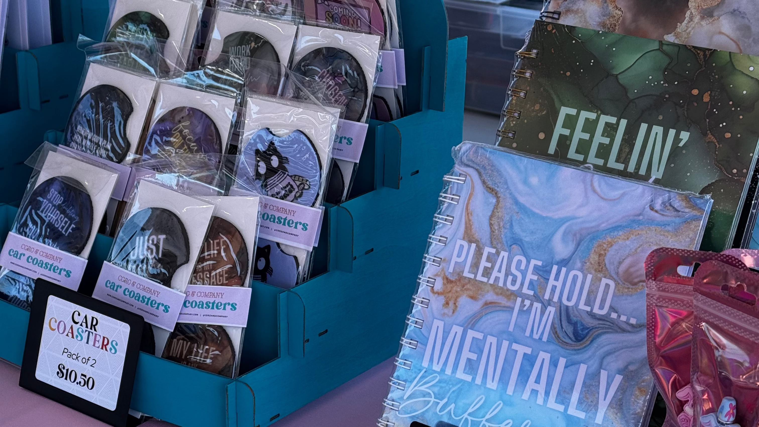 Display of merchandise including books and journals on a table with a pink surface.