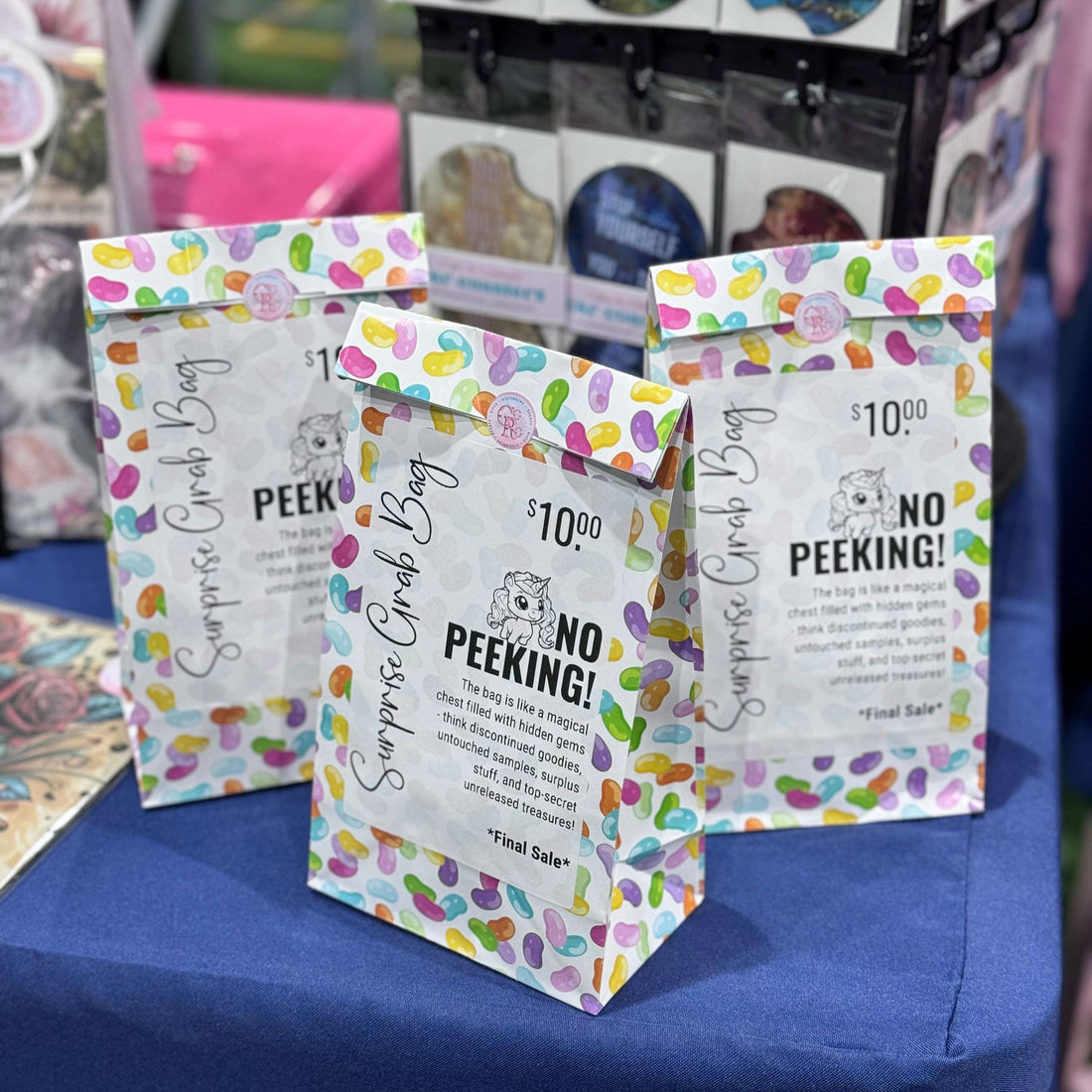 Colorful surprise candy bags with 'No Peeking!' text on a blue surface.
