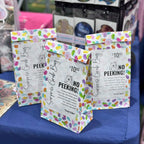 Colorful surprise candy bags with 'No Peeking!' text on a blue surface.