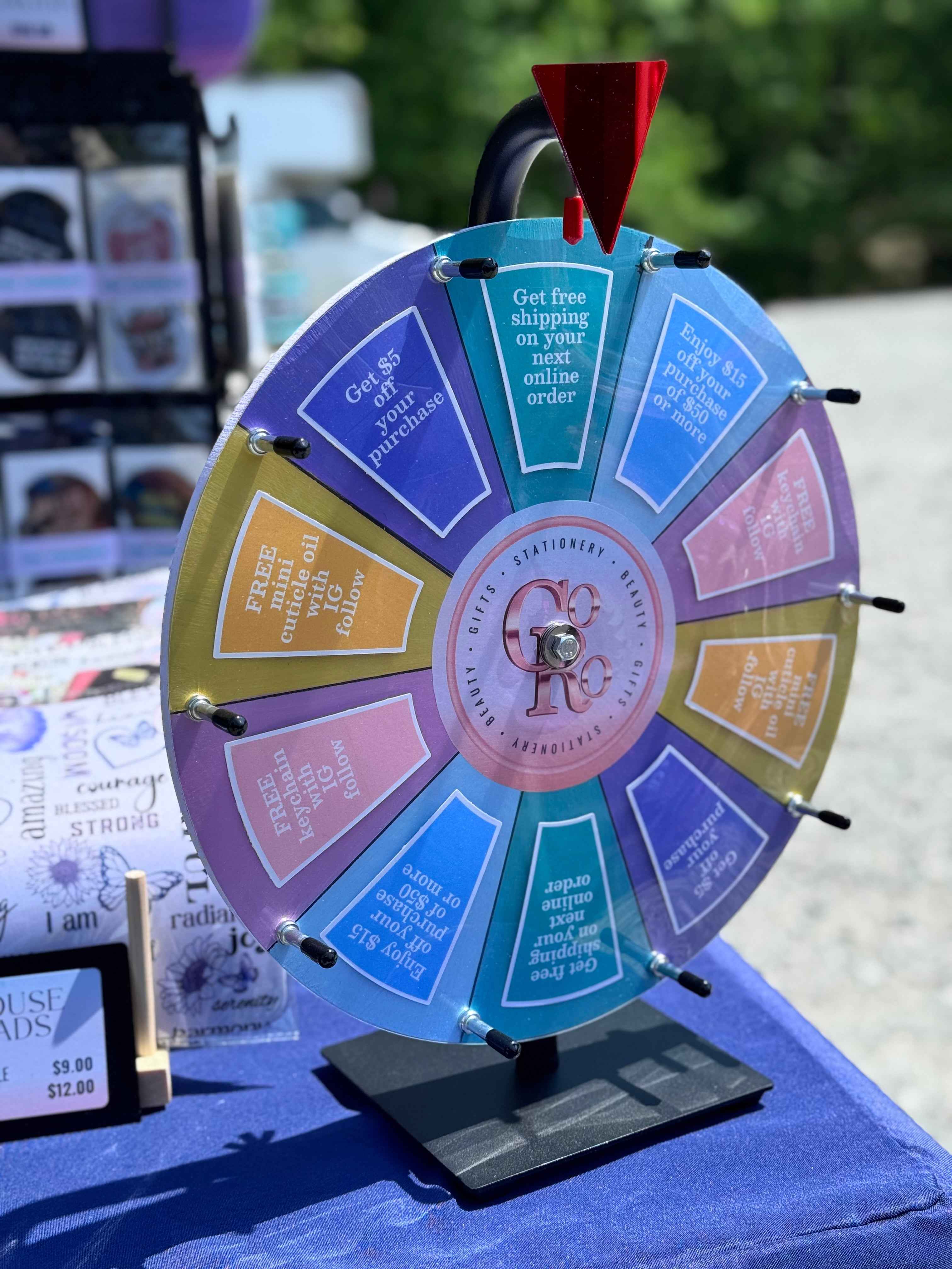 Colorful prize wheel on a stand with text on each section, outdoors.