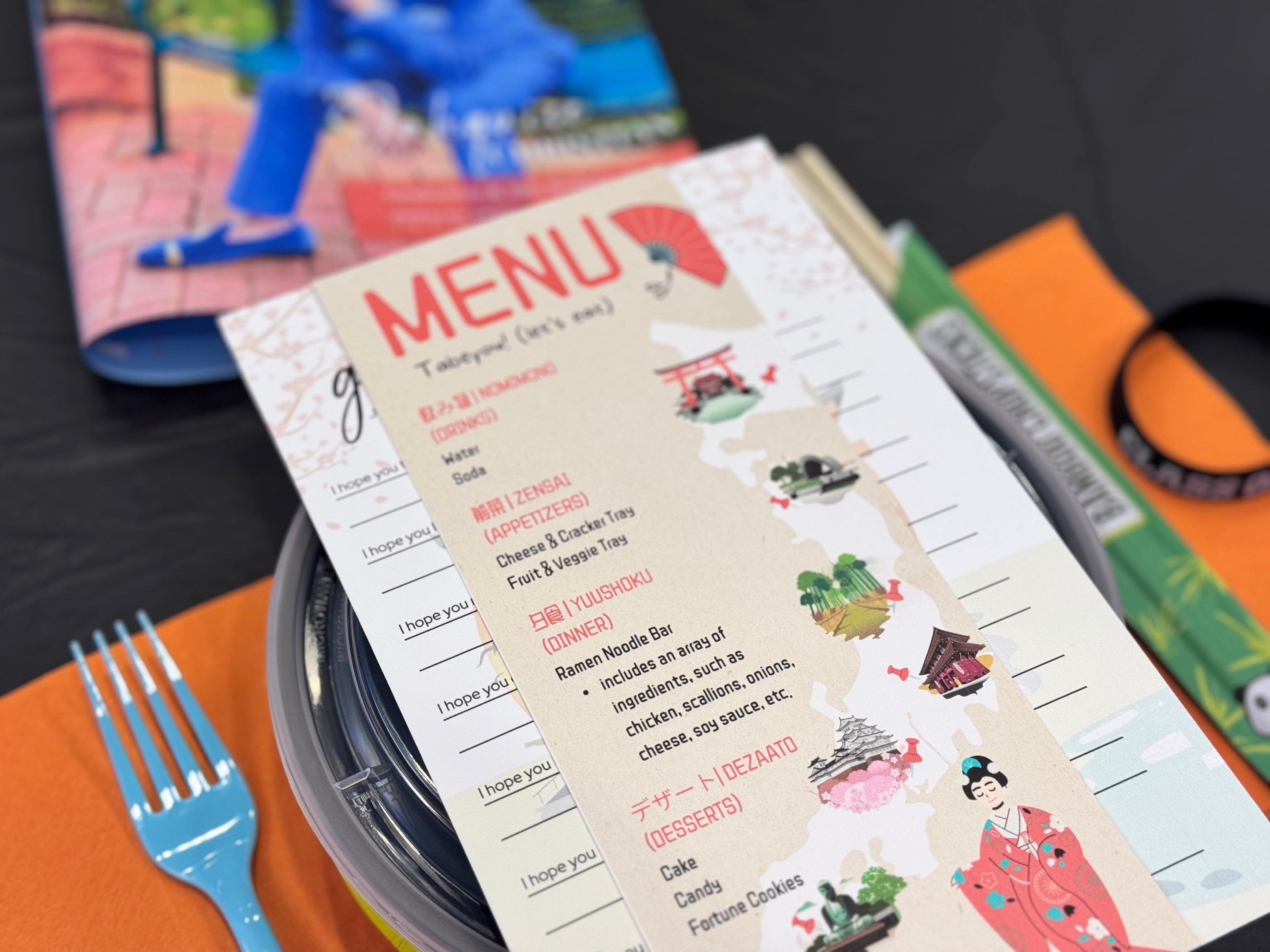Menu with Japanese-themed illustrations on a table with a fork and books.
