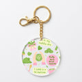 A round acrylic keychain charm featuring a cute matcha-themed illustration with green tea leaves, pink matcha sweets, and the text 'in my matcha era' and 'I LOVE U SO MATCHA'. The charm is attached to a gold-tone metal chain and clasp, shown on a clean white background.