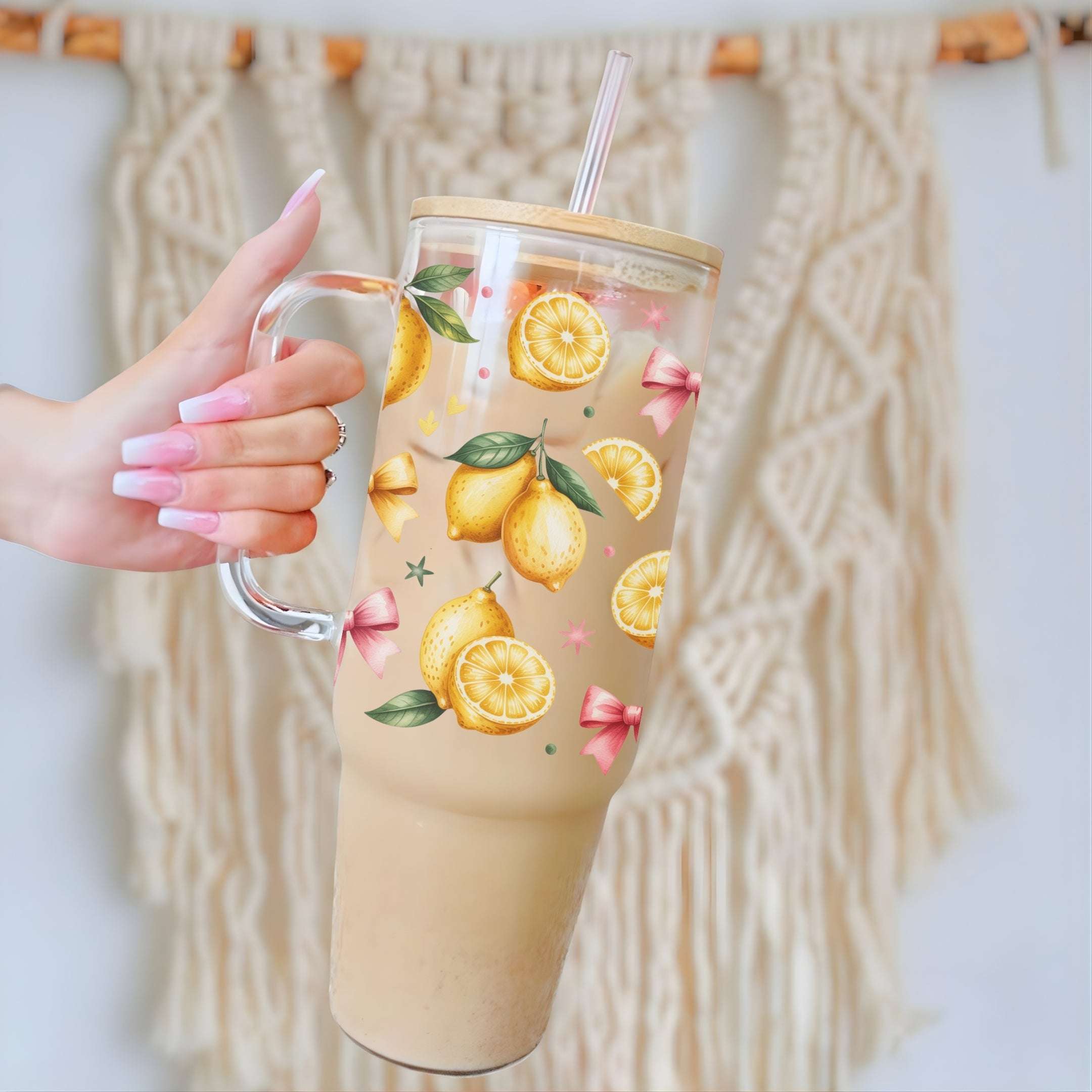 Glass tumbler with lemon design held by a hand against a textured wall.