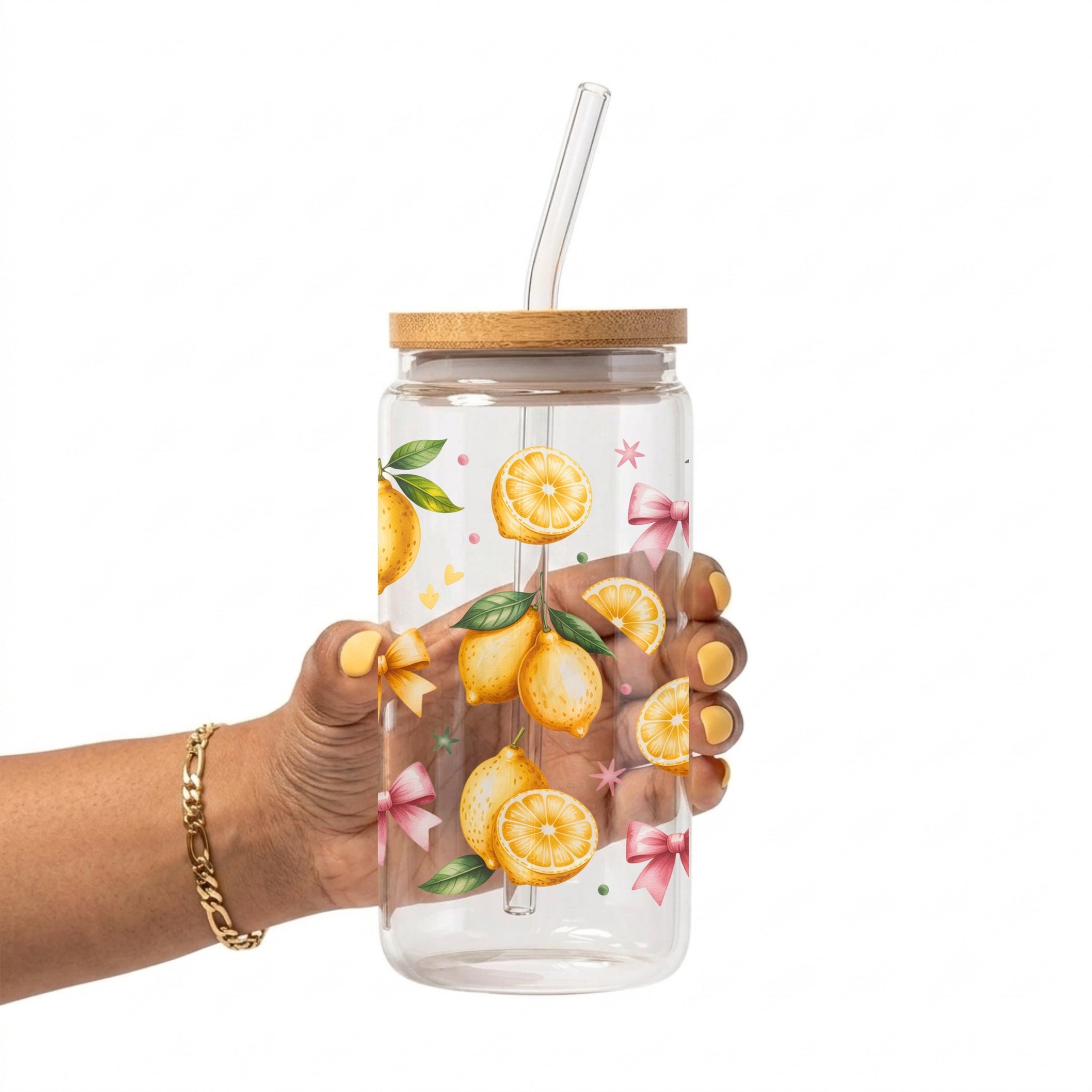 A hand holding a clear plastic water bottle with a bamboo lid and clear glass straw. The bottle is decorated with a watercolor-style pattern of lemons, green leaves, and pink bows.