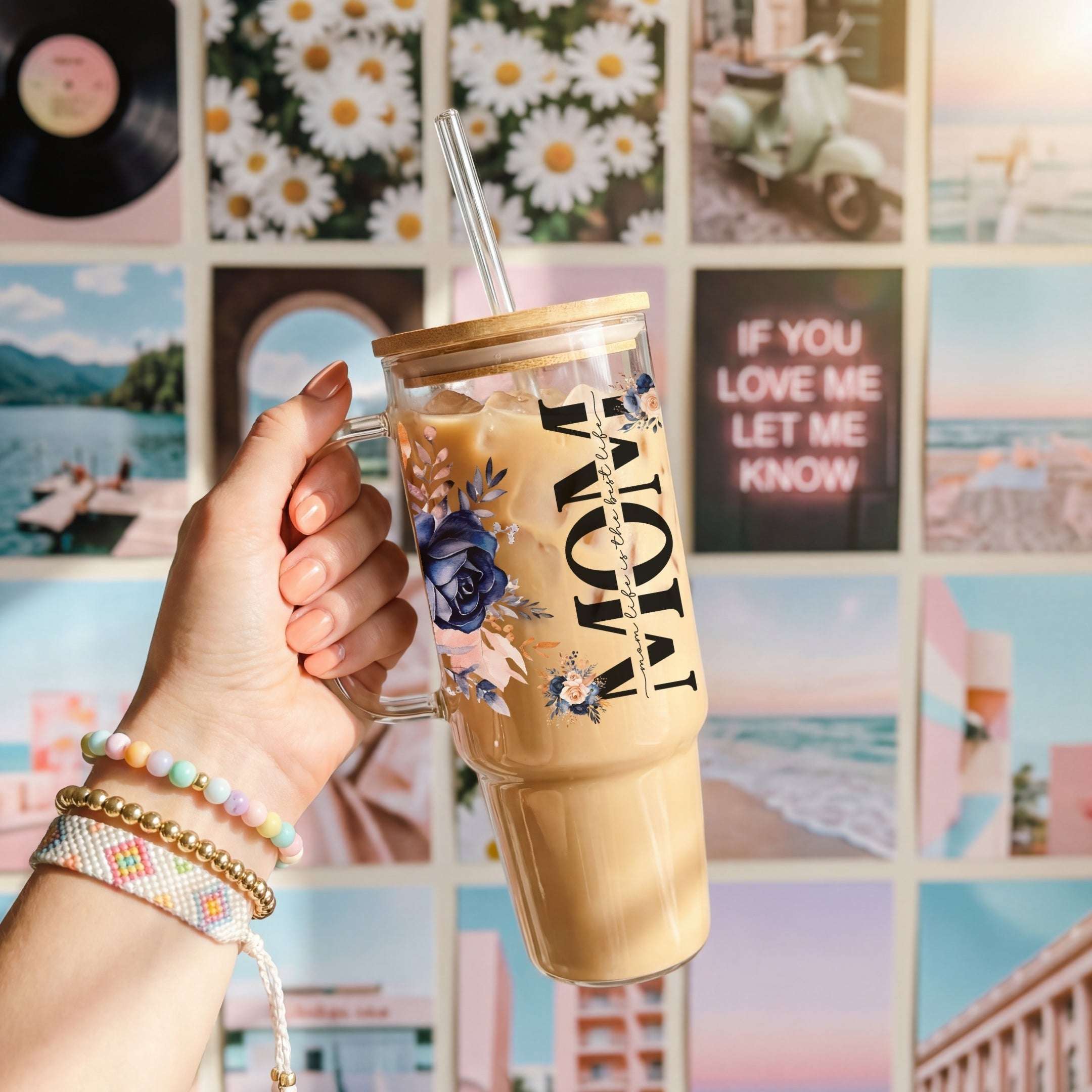 Hand holding a iced coffee tumbler with floral design against a colorful collage background.