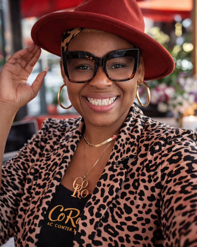 Nik is wearing a burnt orange fedora and leopard print blazer with visible CoRo branding