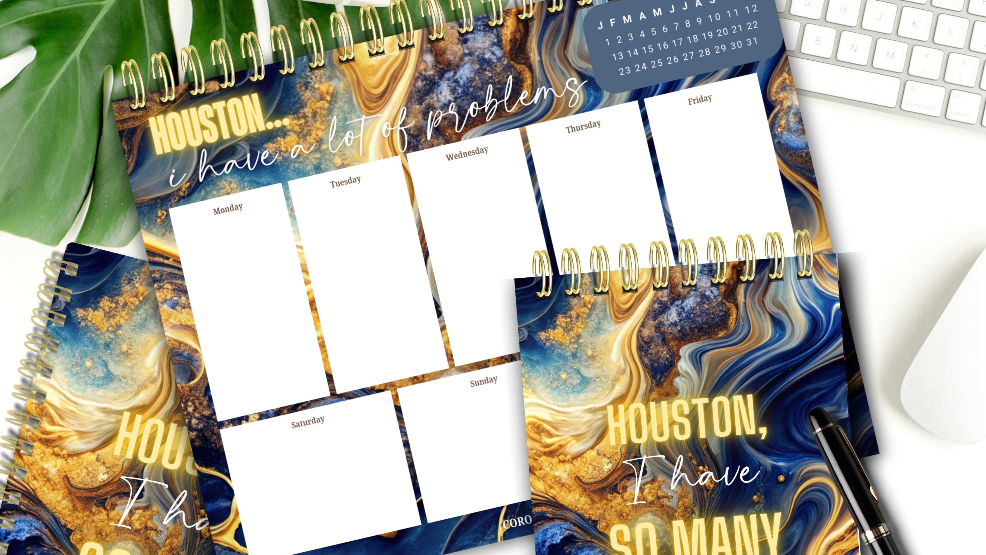 Journal, Notepad, and Weekly Desk Planner with 'Houston, I Have So Many Problems' design on a desk with a keyboard and plant.