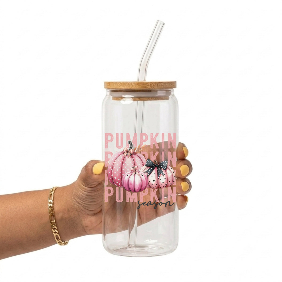 A hand holding a clear 20oz glass tumbler with a bamboo lid and clear straw, featuring a pink and white pumpkin graphic with the text 'PUMPKIN season'.