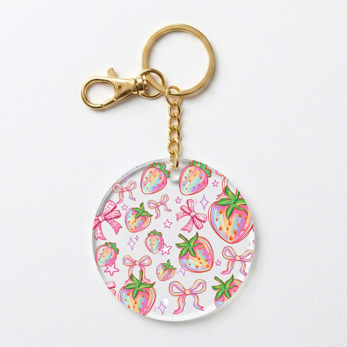 A round acrylic keychain charm featuring a colorful watercolor strawberry and bow pattern, attached to a gold-tone metal split ring and clasp on a plain white background.