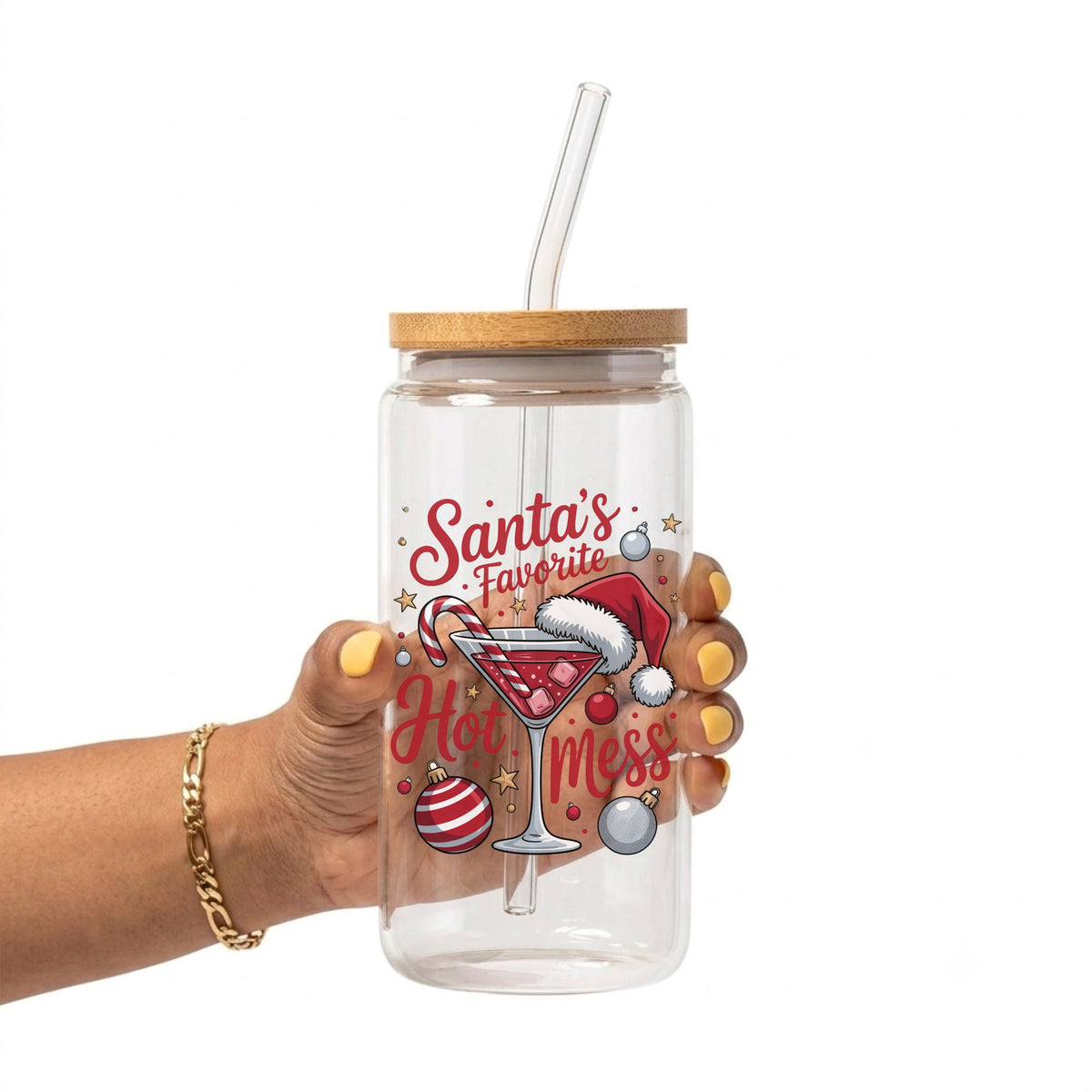 A hand holding a clear plastic tumbler with a bamboo lid and clear straw, featuring a festive 'Santa's Favorite Hot Mess' holiday graphic with a martini glass, candy cane, ornaments, and Santa hat.