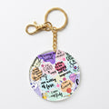 A round acrylic keychain charm featuring colorful self-affirmation quotes, doodles, and small illustrations, attached to a gold-tone split ring and clasp on a white background.
