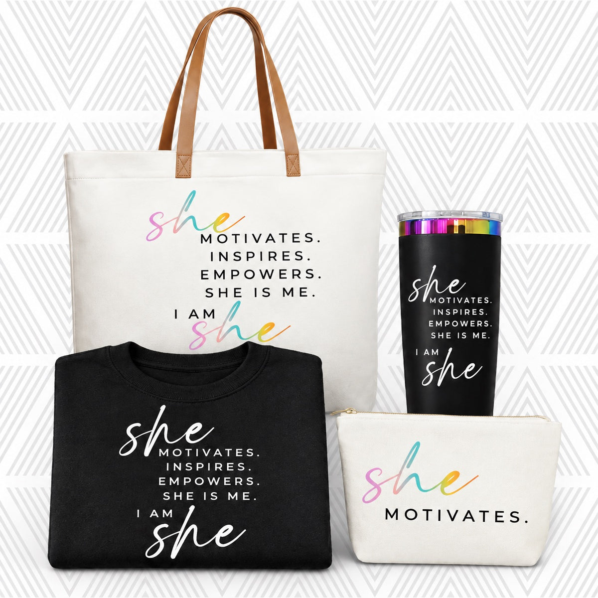 A coordinated gift set featuring a large cream tote bag with tan handles, a black sweatshirt, a cream pouch, and a black insulated tumbler with a rainbow rim, all printed with the phrase 'SHE MOTIVATES.'