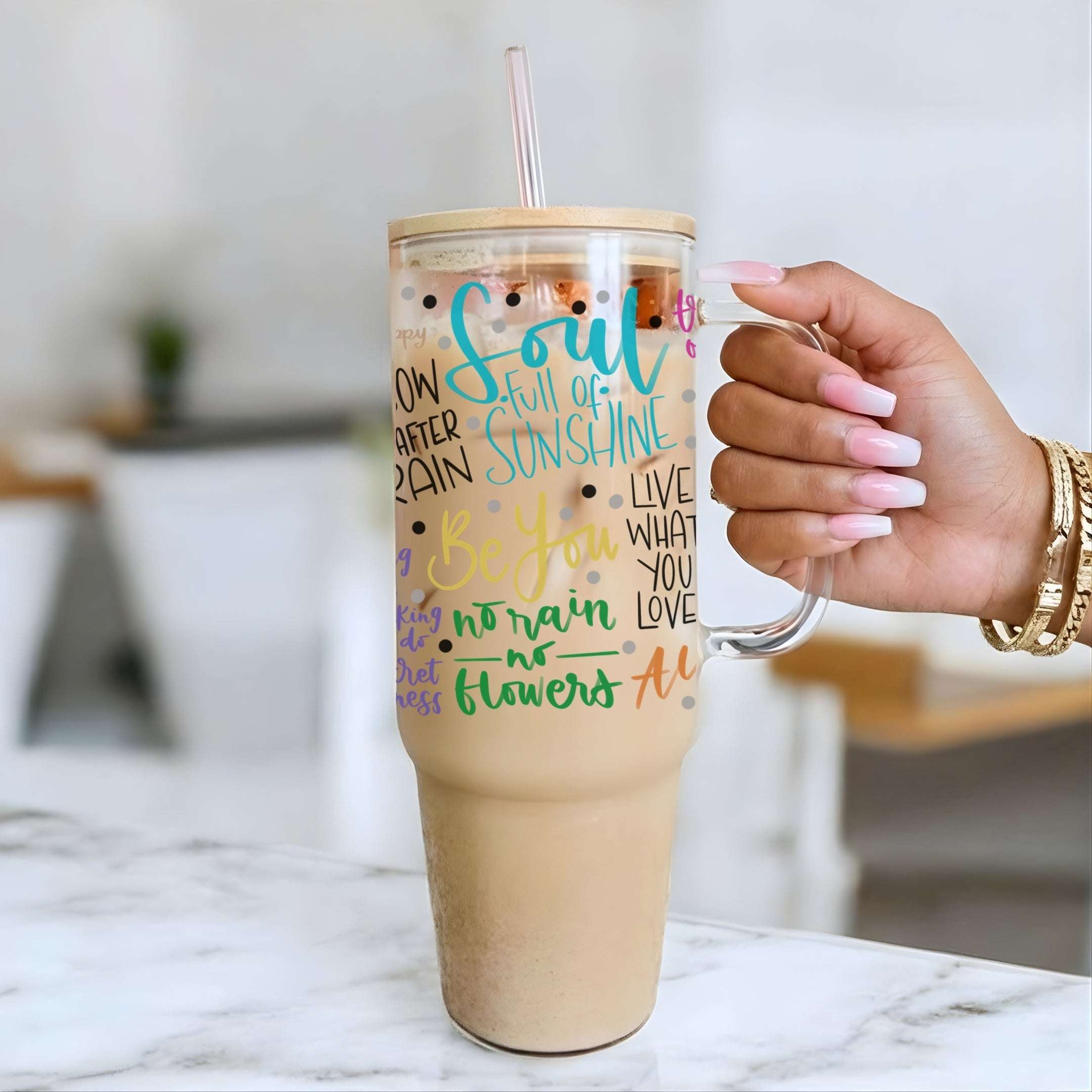 Nik's hand holding a 40oz glass tumbler with Soul Full of Sunshine design on a marble surface.