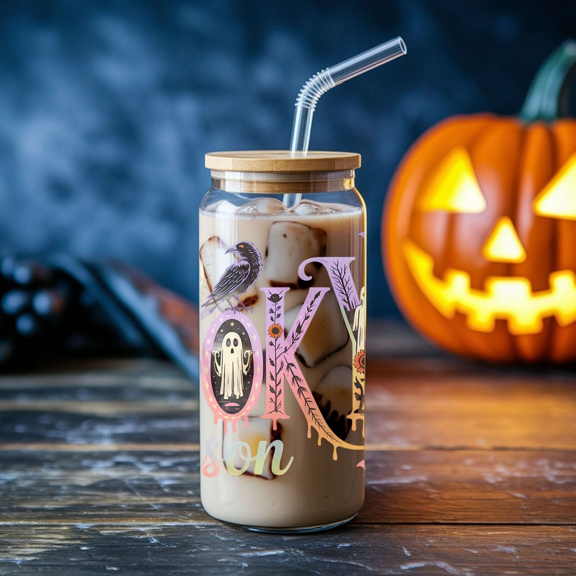 Halloween-themed glass cup with a straw, pumpkin in the background