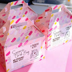 Pink 'Surprise Grab Bag' boxes with colorful patterns on a pink background.