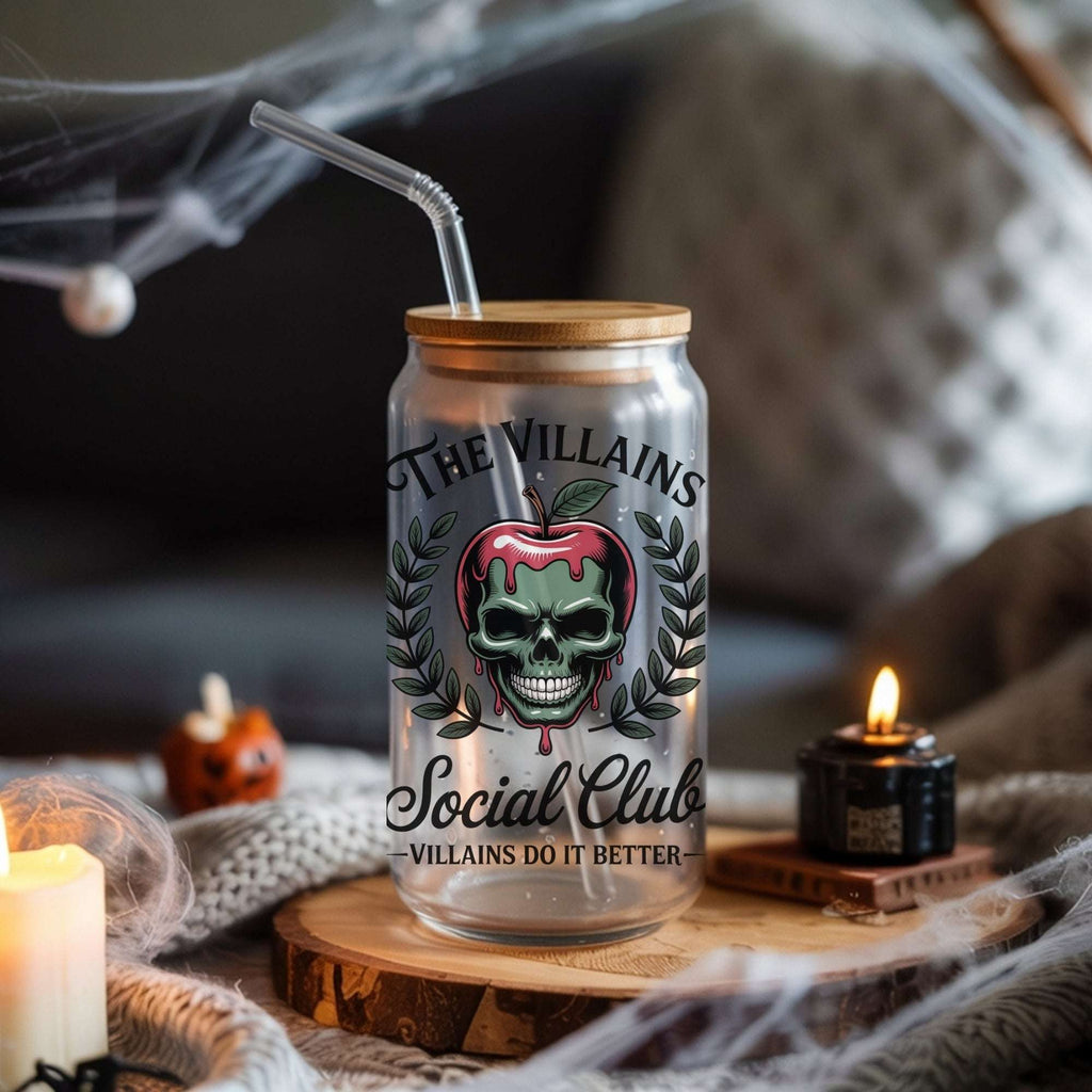 Glass cup with wooden lid and Halloween-themed label on a table with candles and pumpkins.