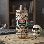Glass tumbler with skull design and text on a table with a skull and bookshelf in the background
