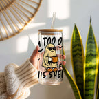 Clear tumbler with cartoon ghost holding a coffee cup and text, held by a person in a home setting.
