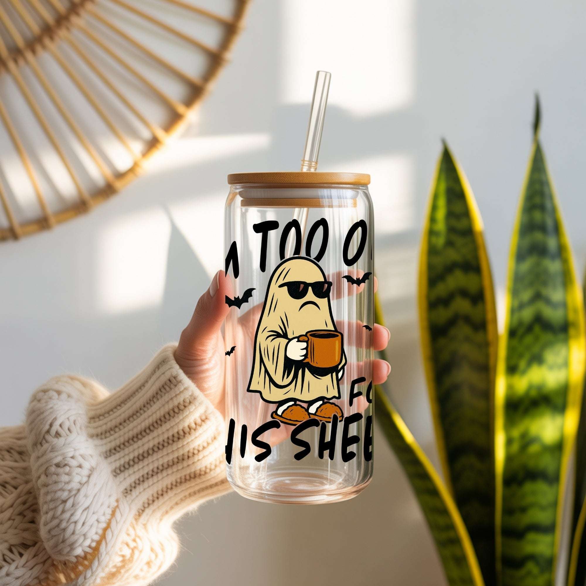 Clear tumbler with cartoon ghost holding a coffee cup and text, held by a person in a home setting.