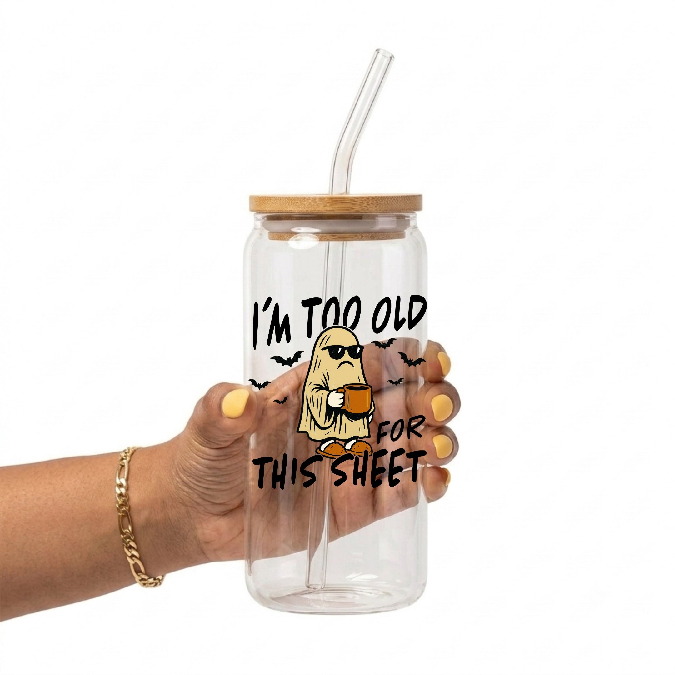 A hand holding a clear glass tumbler with a bamboo lid and clear straw, featuring a cartoon ghost graphic and the text 'I'M TOO OLD FOR THIS SHEET' on a white background.