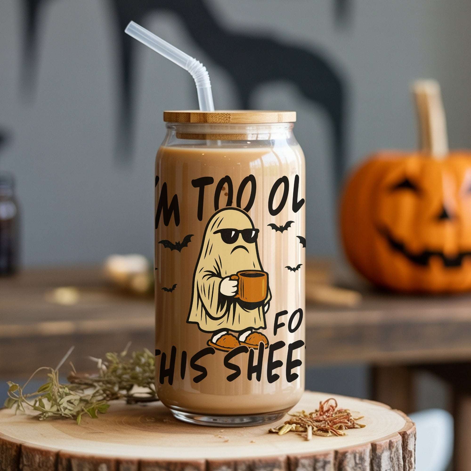 Glass tumbler with Halloween-themed design and text on a wooden surface with pumpkins in the background