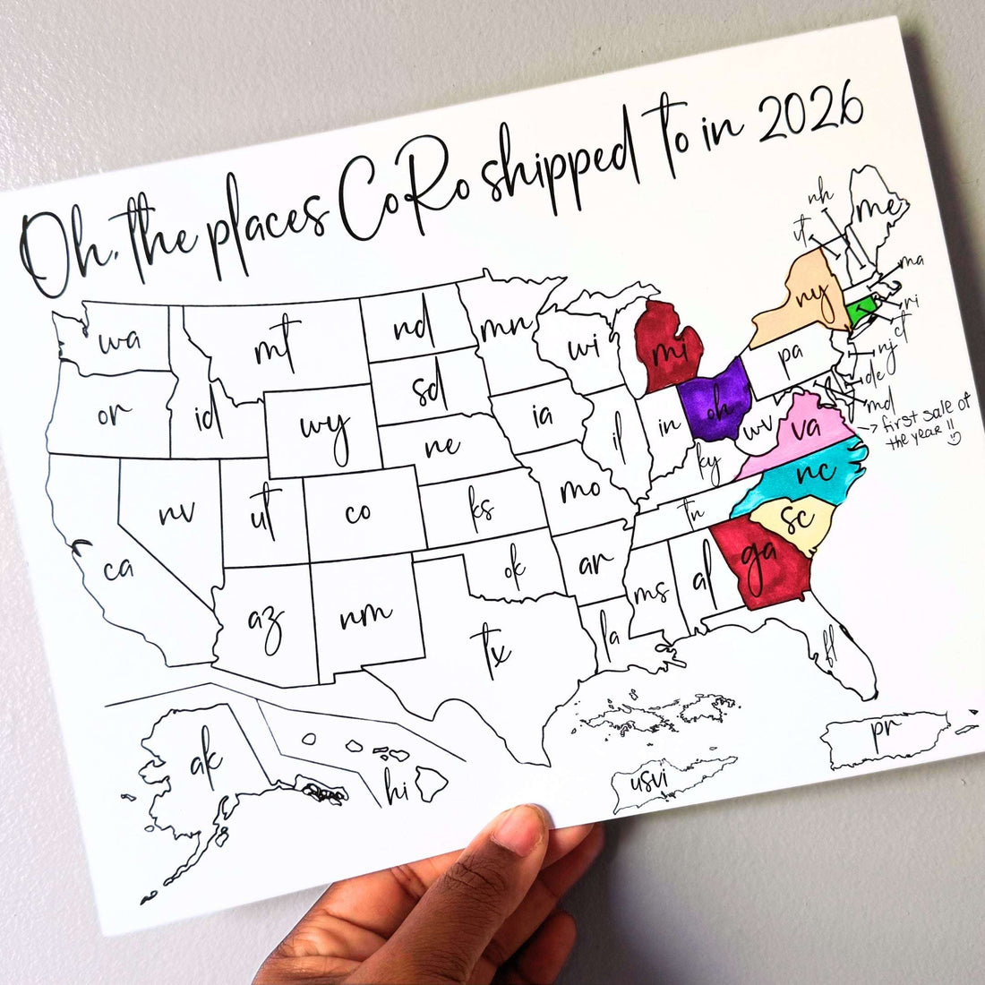 Map of the United States with colored boxes labeled 'Oh, the places CoRo shipped to in 2026' held by the owner's hand.