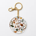 A round acrylic keychain charm featuring a western-themed doodle pattern with a gold-tone split ring and clasp, shown on a clean white background.