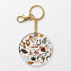 A round acrylic keychain charm featuring a western-themed doodle pattern with a gold-tone split ring and clasp, shown on a clean white background.