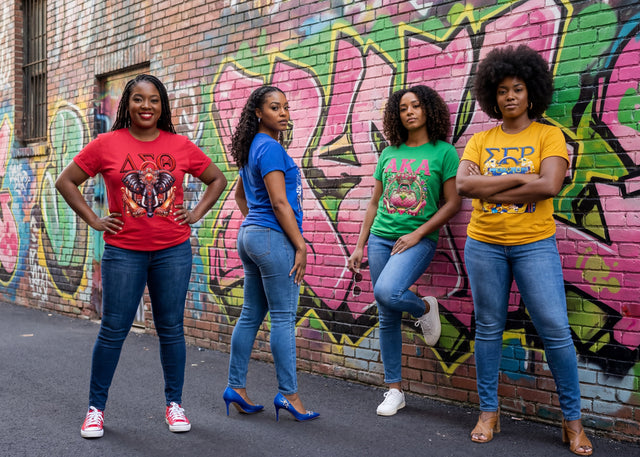 Four sorority women standing in front of a graffiti-covered wall.