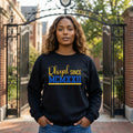 SGRho woman wearing a black sweatshirt with 'Rhoyal Since MCMXXII' text in front of a gate.