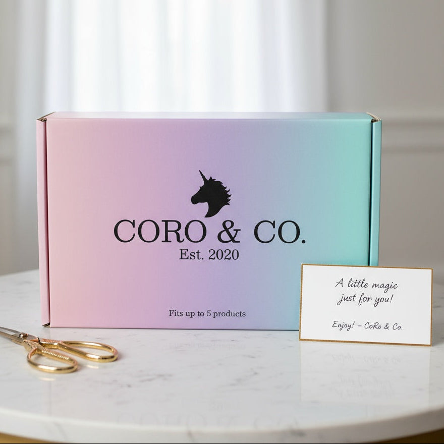Gradient box with 'CORO & CO.' branding on a marble surface with a card and scissors.