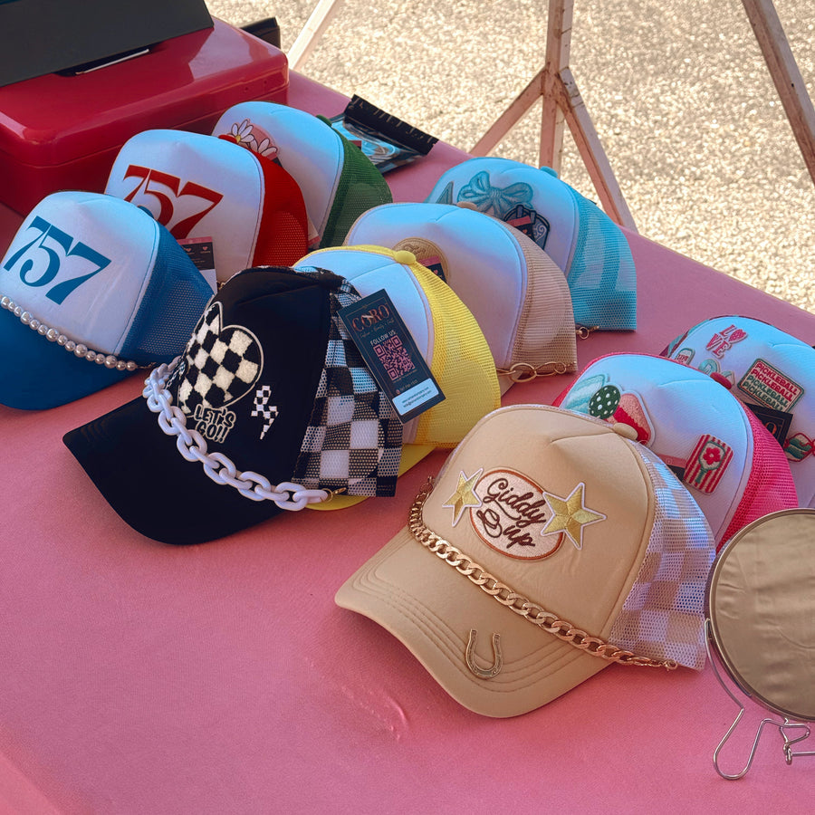 Collection of various hats on a pink surface with a blurred background